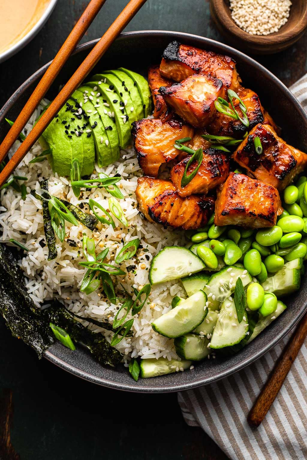 Crispy salmon and rice bowl with avocado, cucumber, and edamame on top 