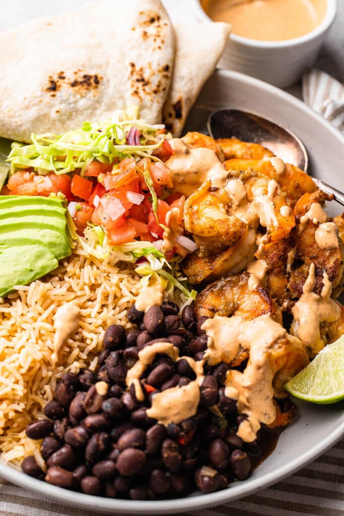 A shrimp burrito bowl topped with chipotle sauce 