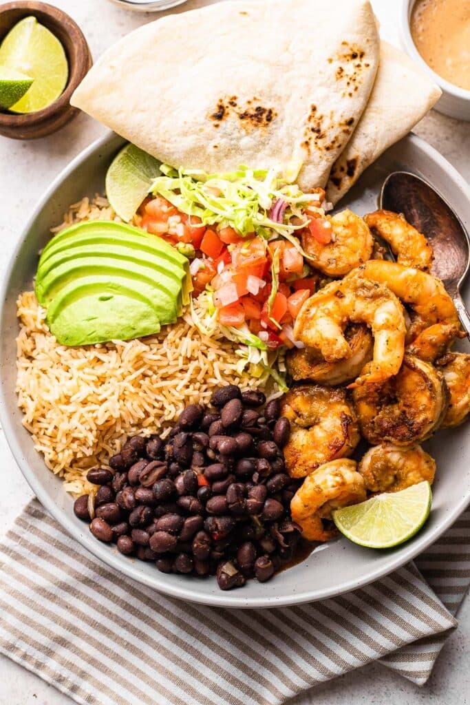 A shrimp burrito bowl with a tortilla 