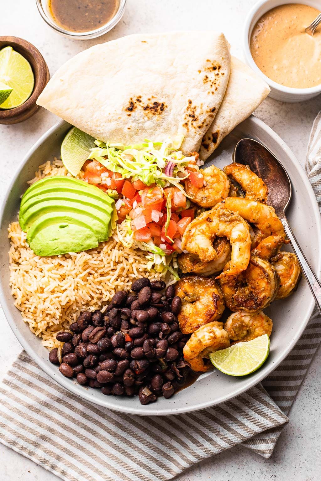 A shrimp burrito bowl with a tortilla on the side 