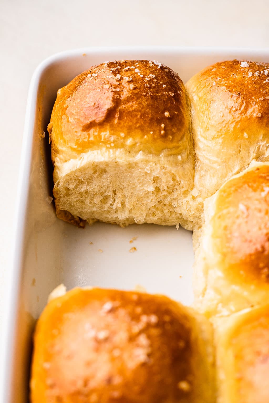 A close up look at brioche dinner rolls, with one missing 