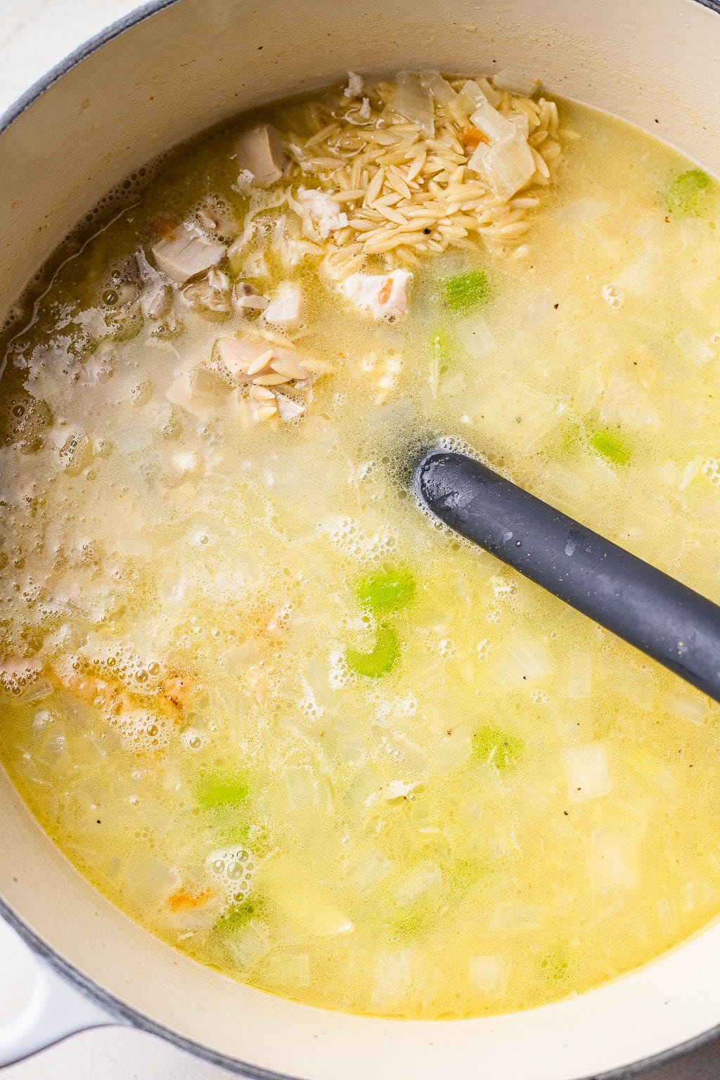 Chicken orzo soup simmering in a pot 
