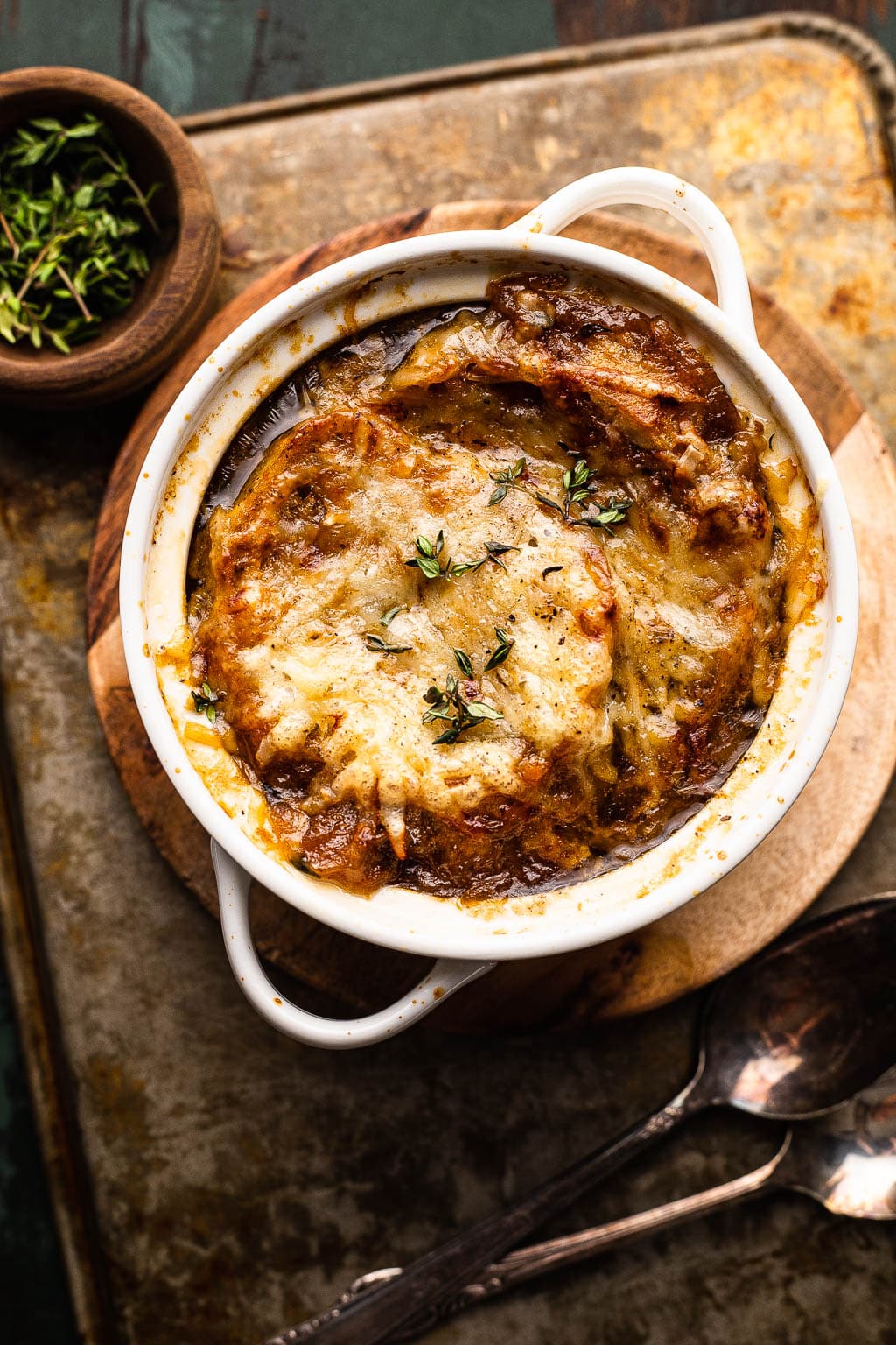 A ramekin of homemade French onion soup topped with toasted bread and shredded Gruyere. 