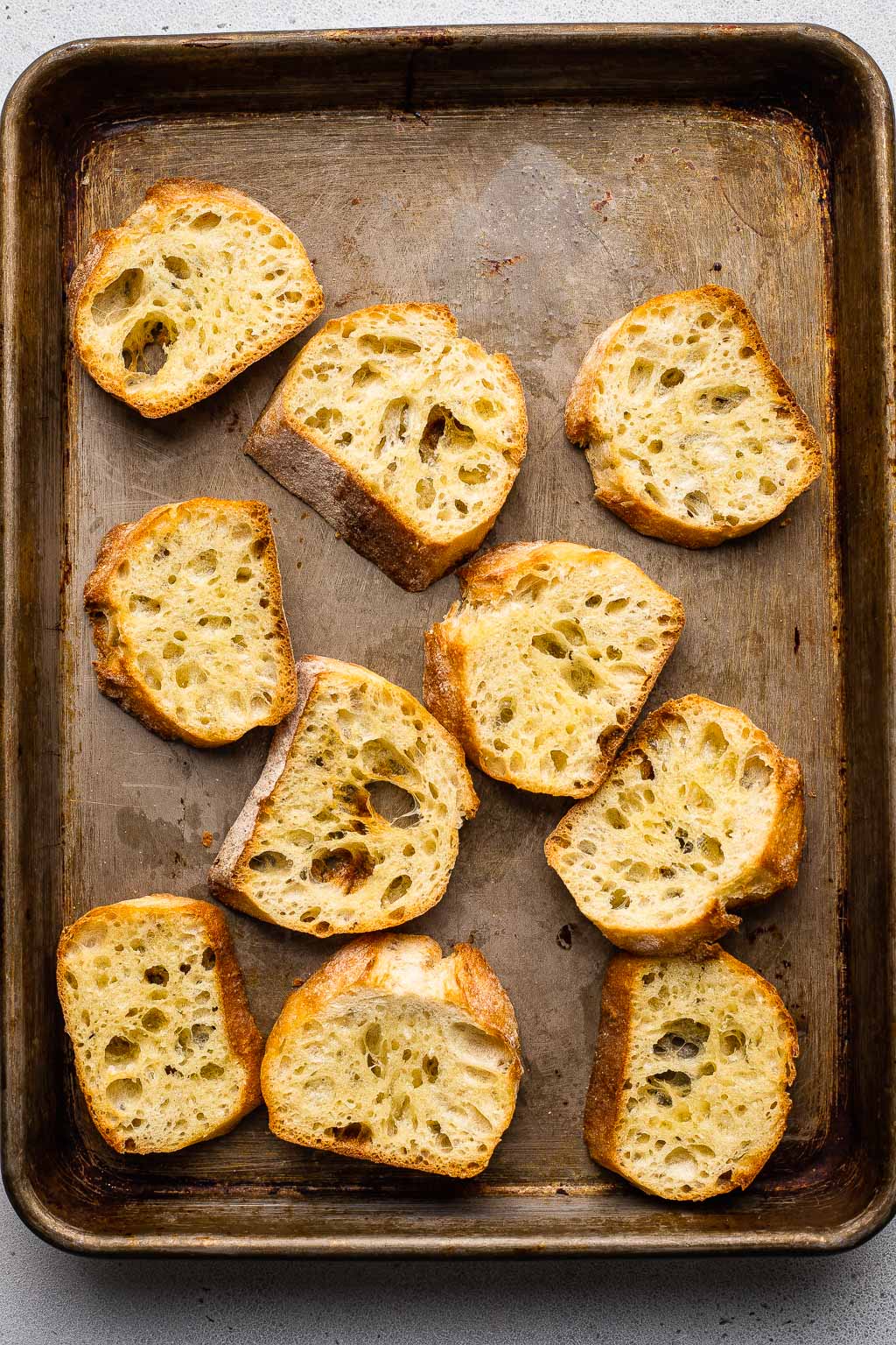 Toasted baguette slices on a baking sheet. 