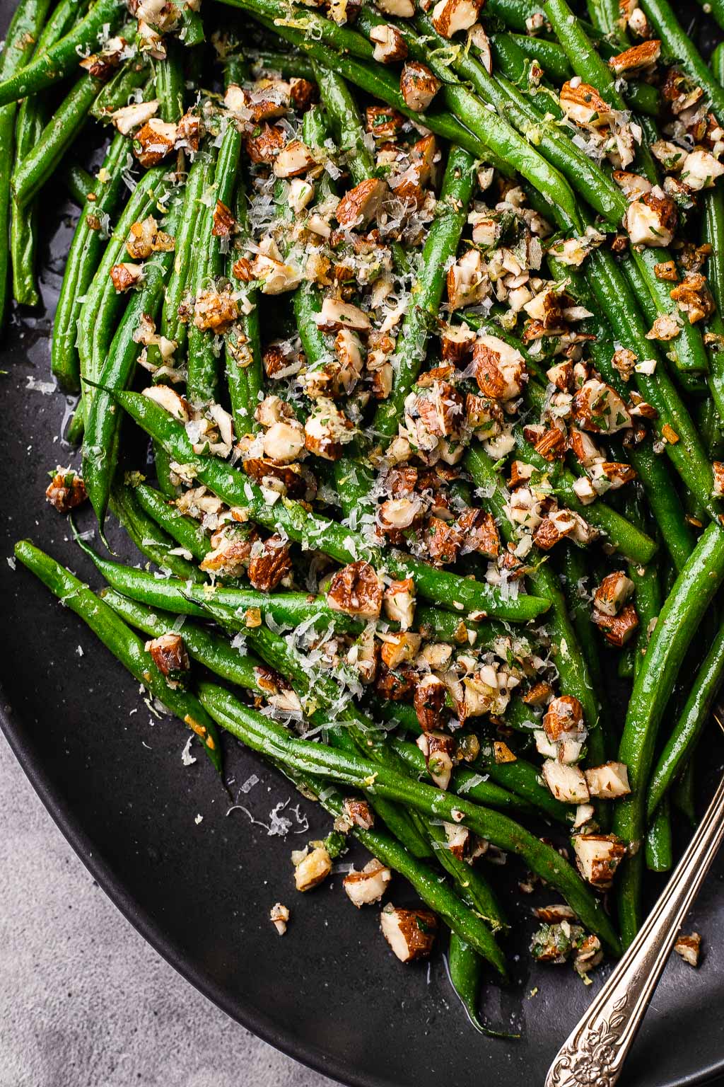 Sautéed green beans topped with almond and lemon gremolata on a platter 