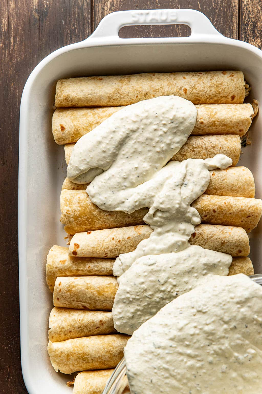 sauce poured on the enchiladas in a baking dish