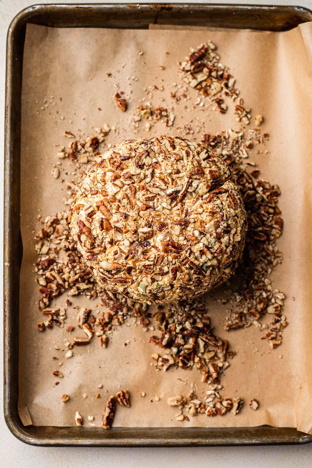 A cheese ball after being coated in pecans