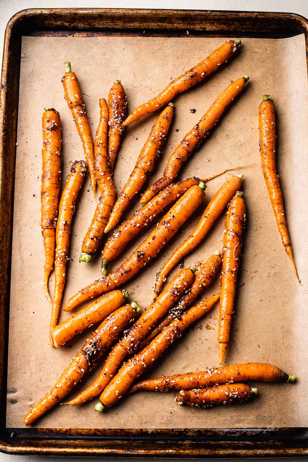 Whole carrots on a baking sheet, ready to be roasted 