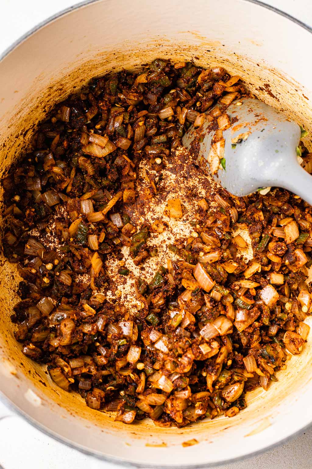 Spices and aromatics for chili in a pot. 