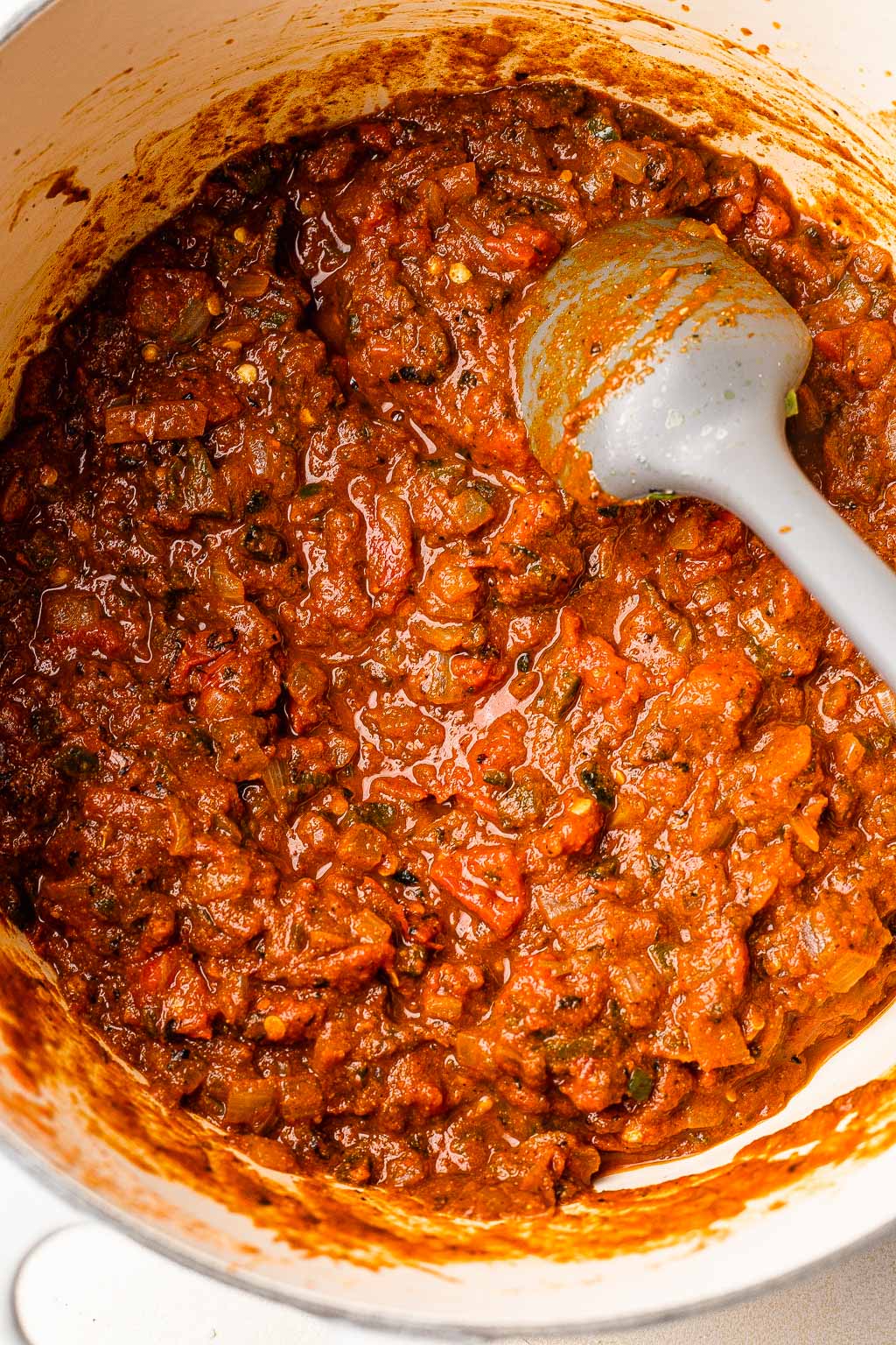 Canned tomatoes added to a pot of chili. 