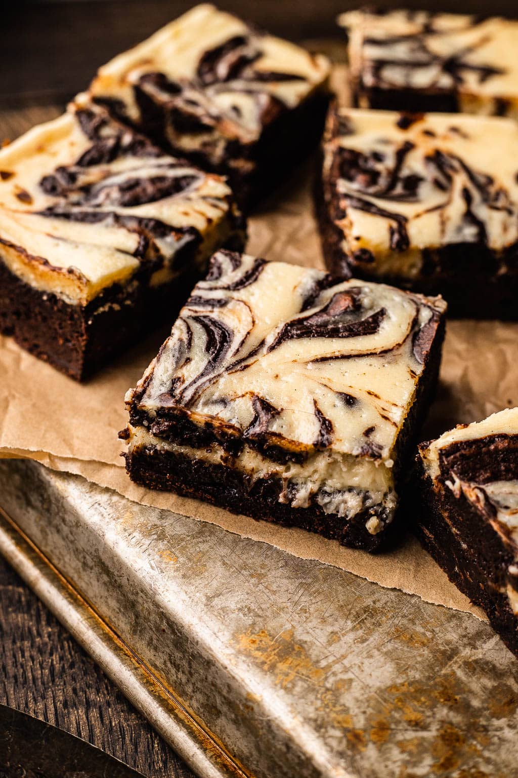Sliced marbled cheesecake brownies on parchment paper