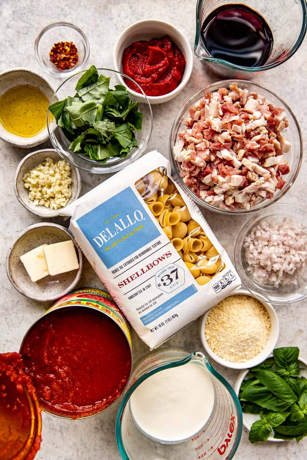 Pink sauce pasta ingredients laid out on a light background. 