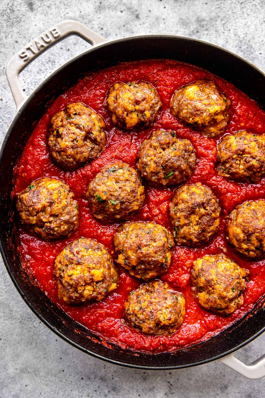 Baked ricotta meatballs in a pan of tomato sauce 