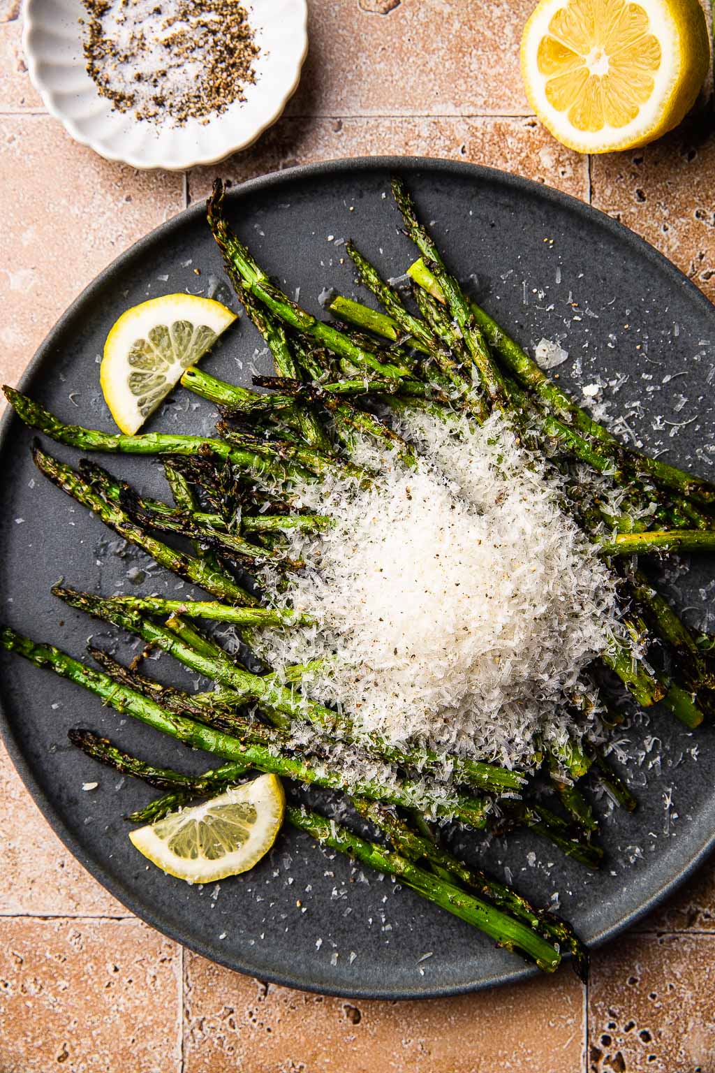 A plate of grilled asparagus topped with grated parmesan