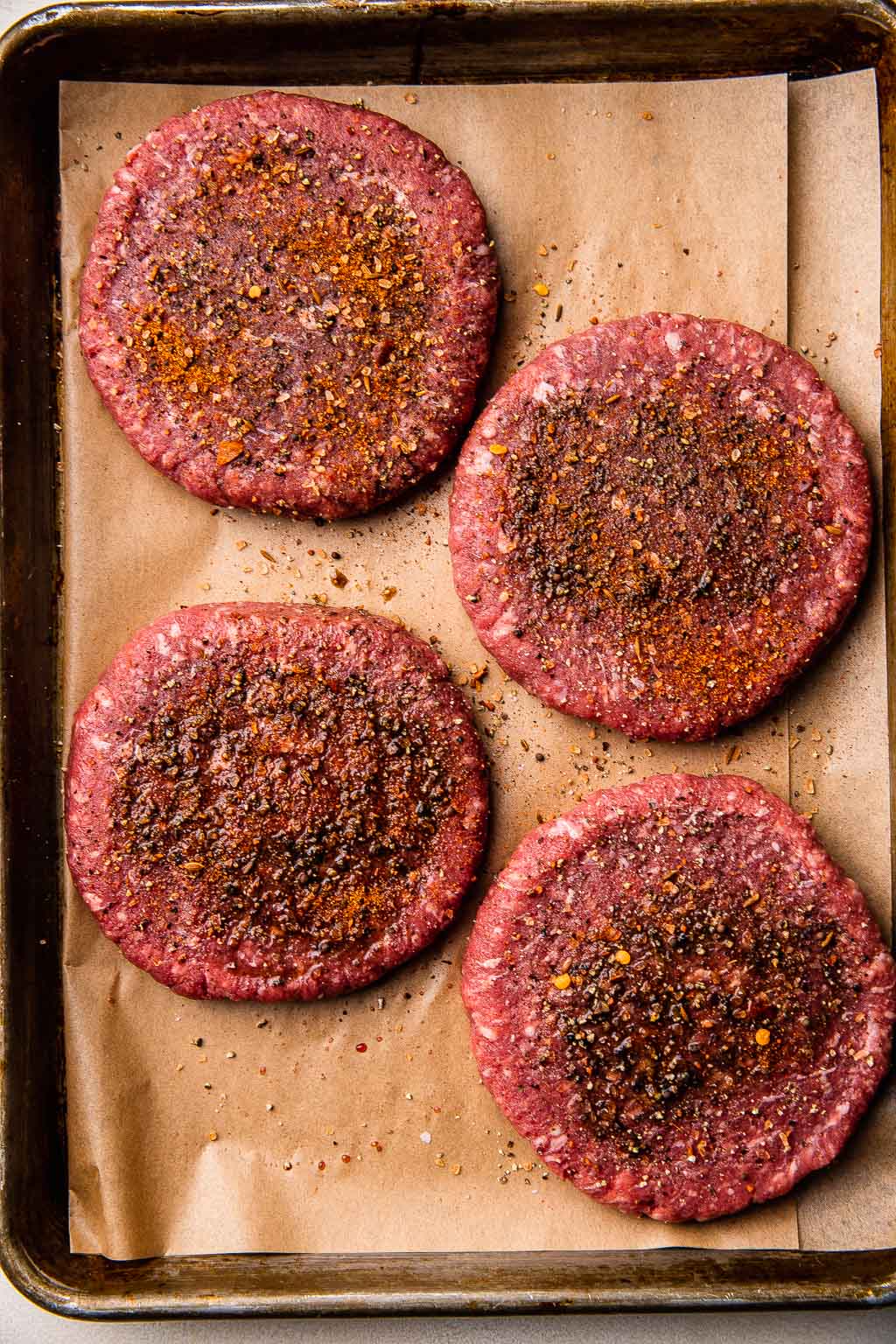 Fresh burger patties seasoned with salt and pepper 