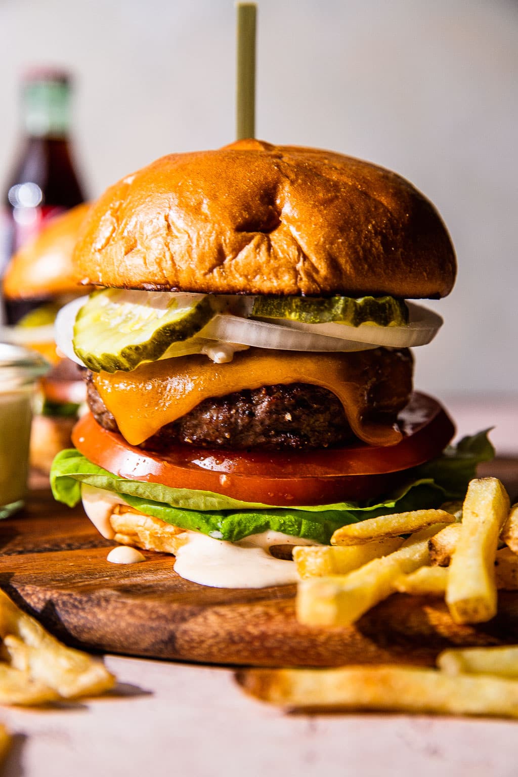 A cheeseburger topped with pickle, tomato, onion, and lettuce