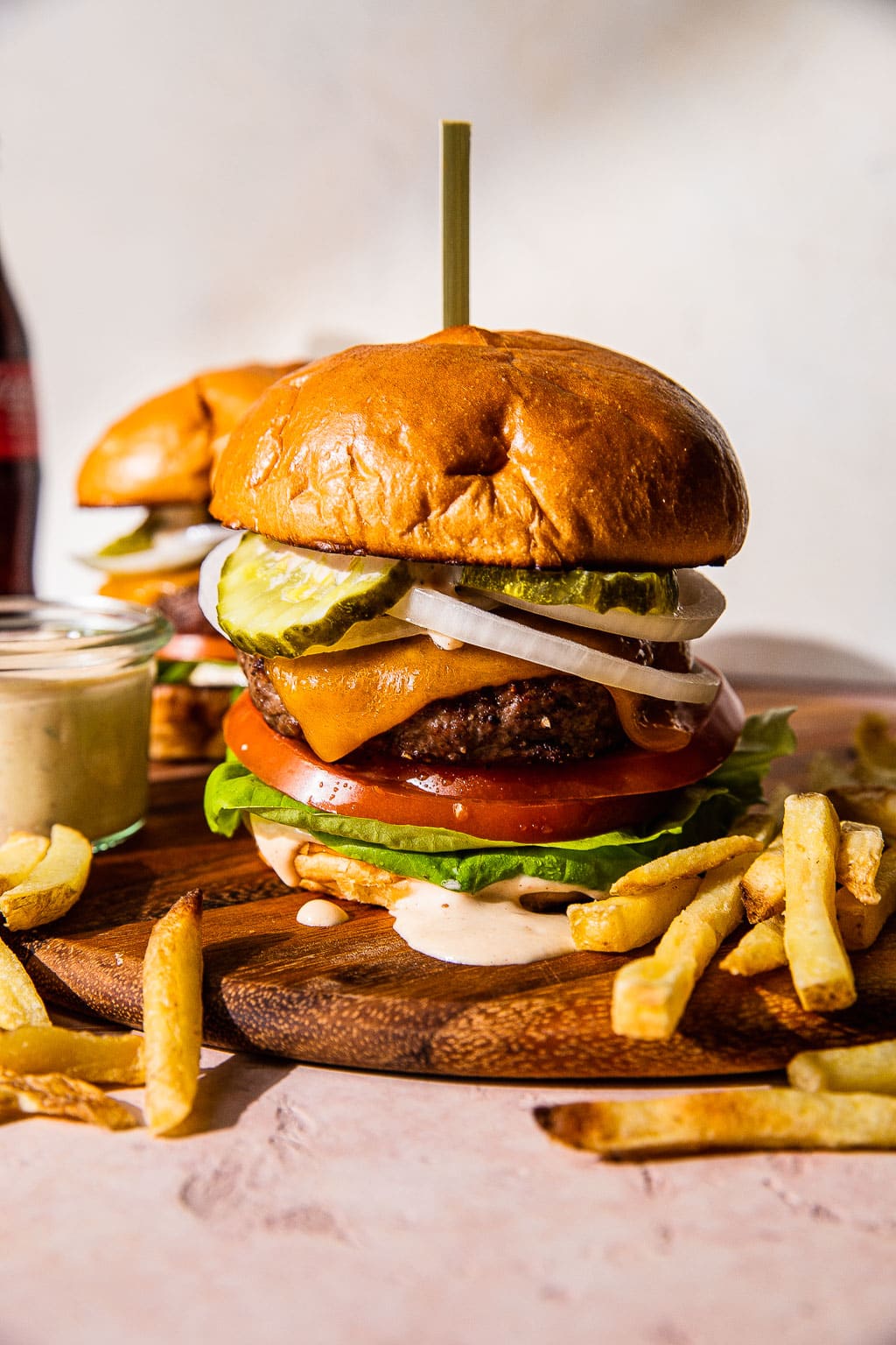 A cheeseburger topped with pickle, tomato, onion, and lettuce