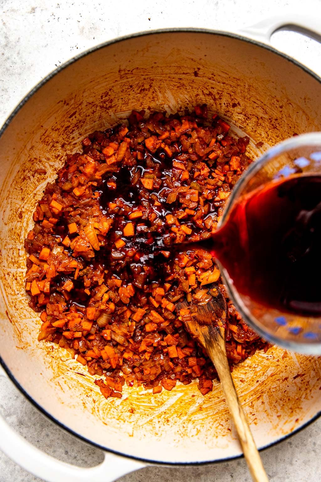 Red wine being poured into a Dutch oven 
