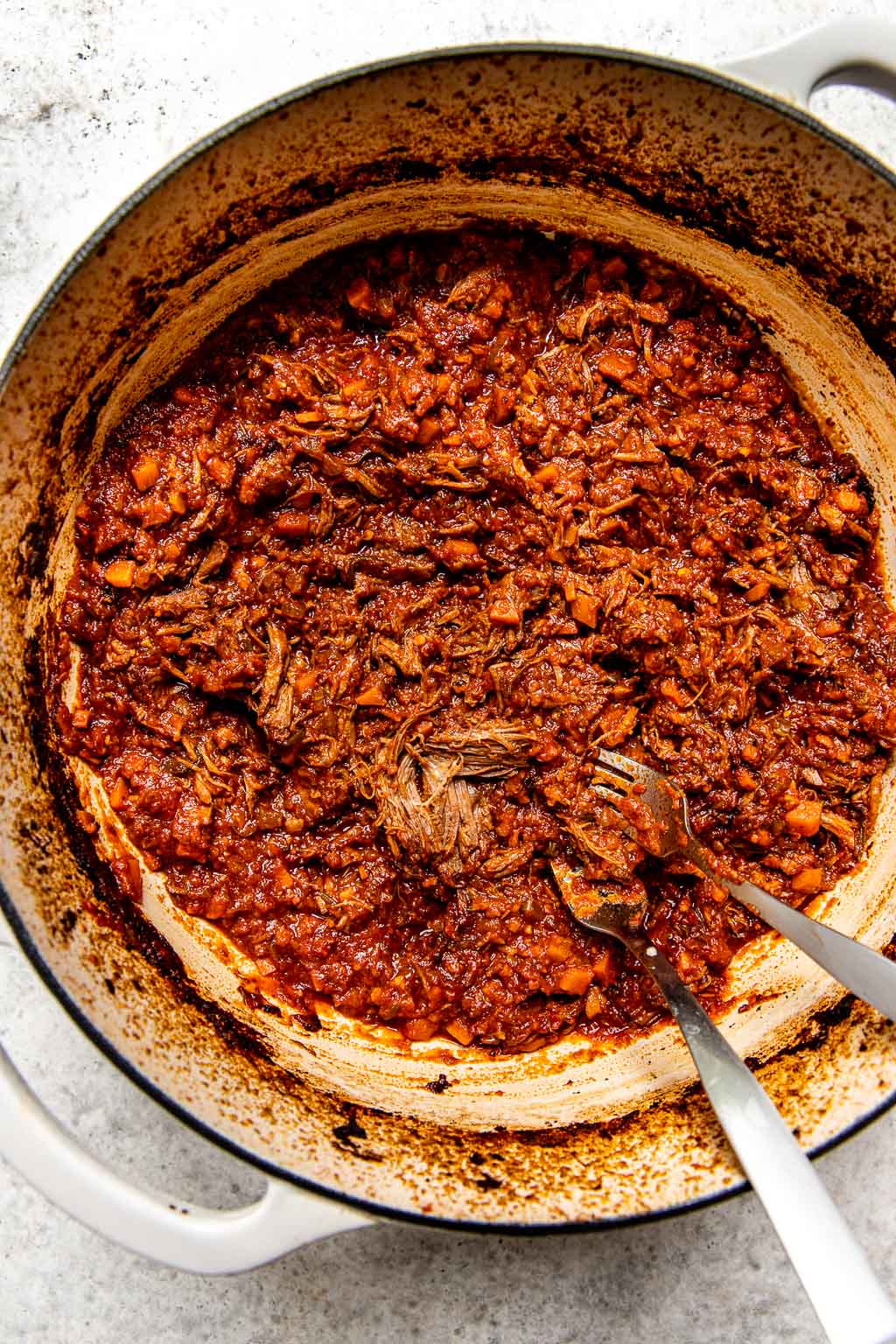 Beef being shredded in a Dutch oven 