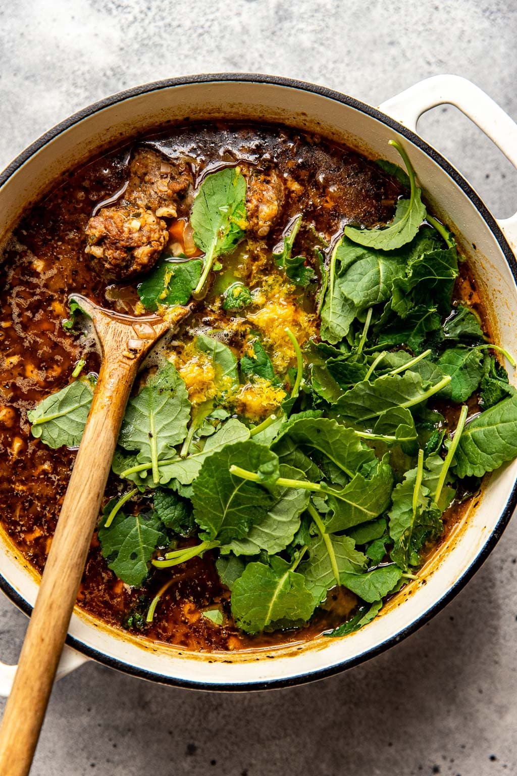 Baby kale being added to Italian wedding soup 