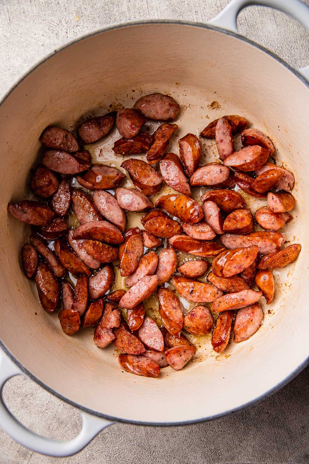 Kielbasa slices browning in Dutch oven