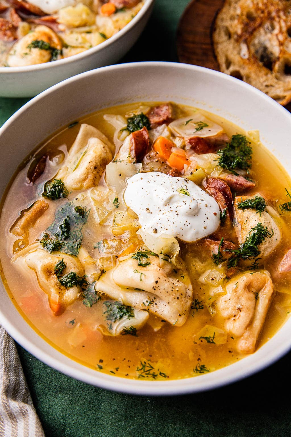A bowl of pierogi soup topped with sour cream