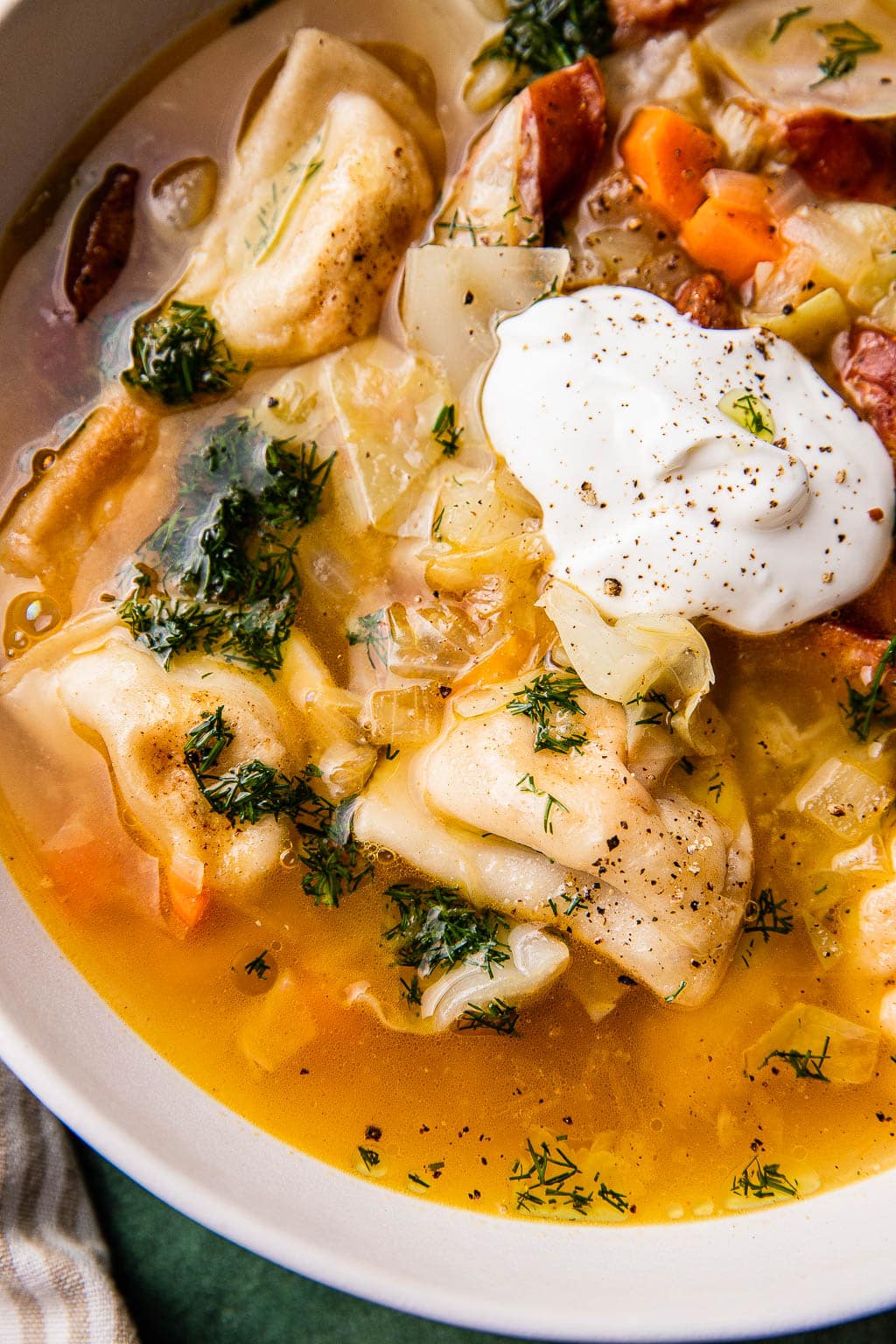 A bowl of pierogi soup topped with sour cream