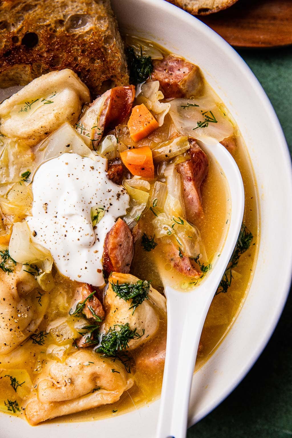 A bowl of pierogi soup topped with sour cream