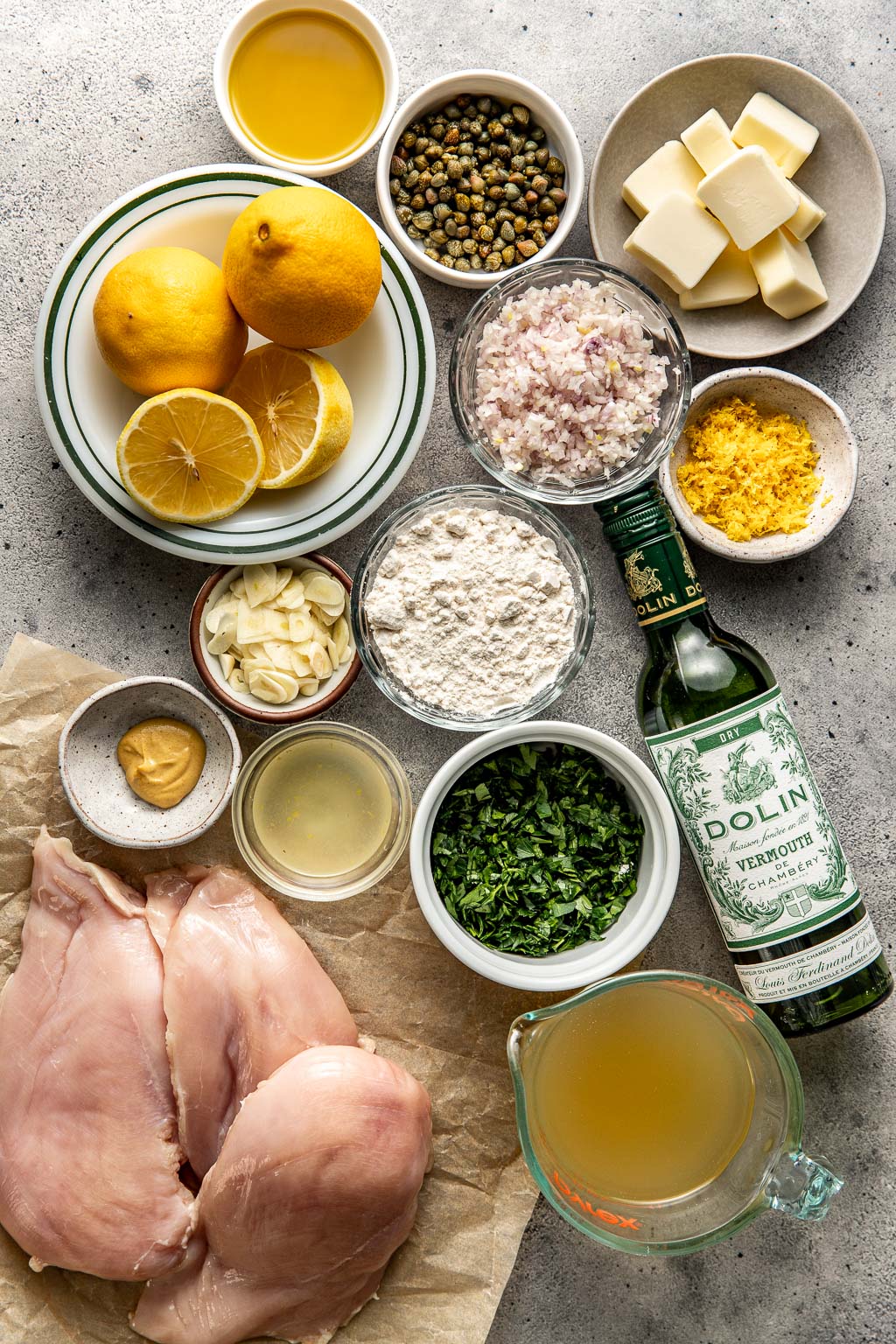 Chicken piccata ingredients laid out on a gray background