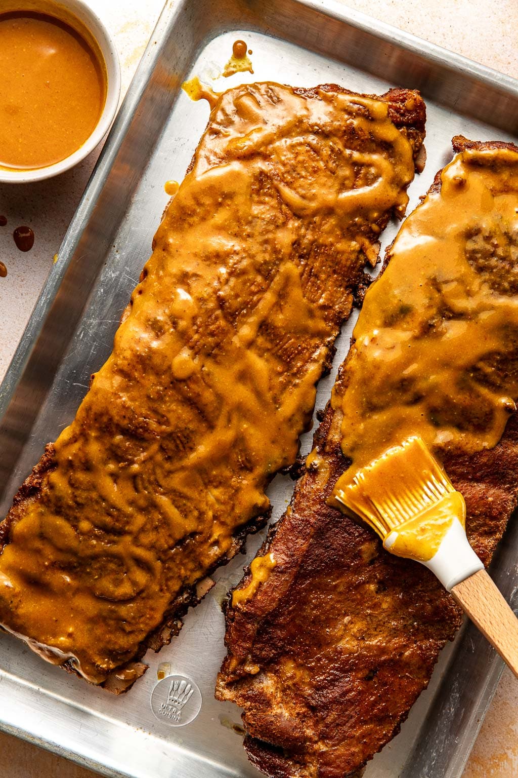 ribs being brushed with Carolina gold bbq sauce