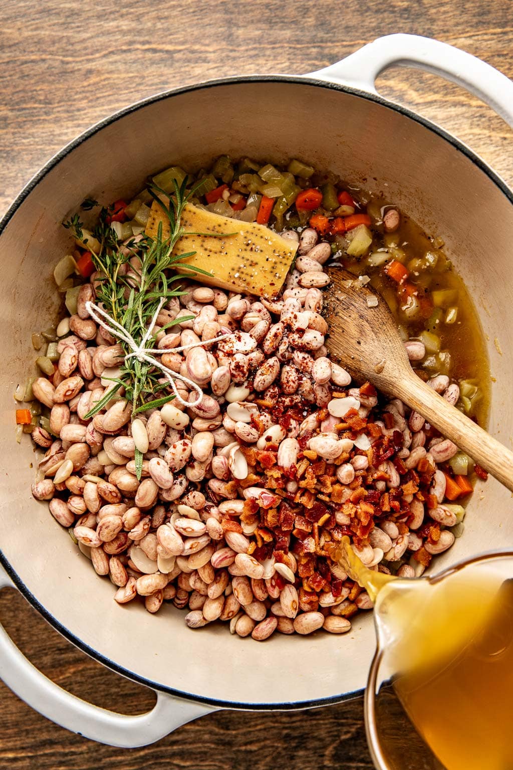 broth being poured over beans in a dutch oven