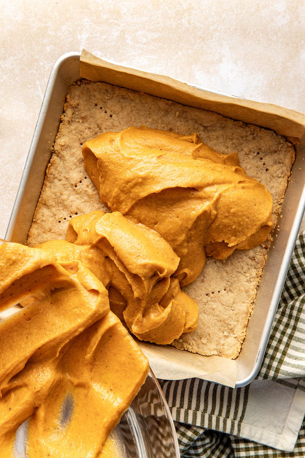 Sweet potato pie filling being poured over a shortbread crust. 