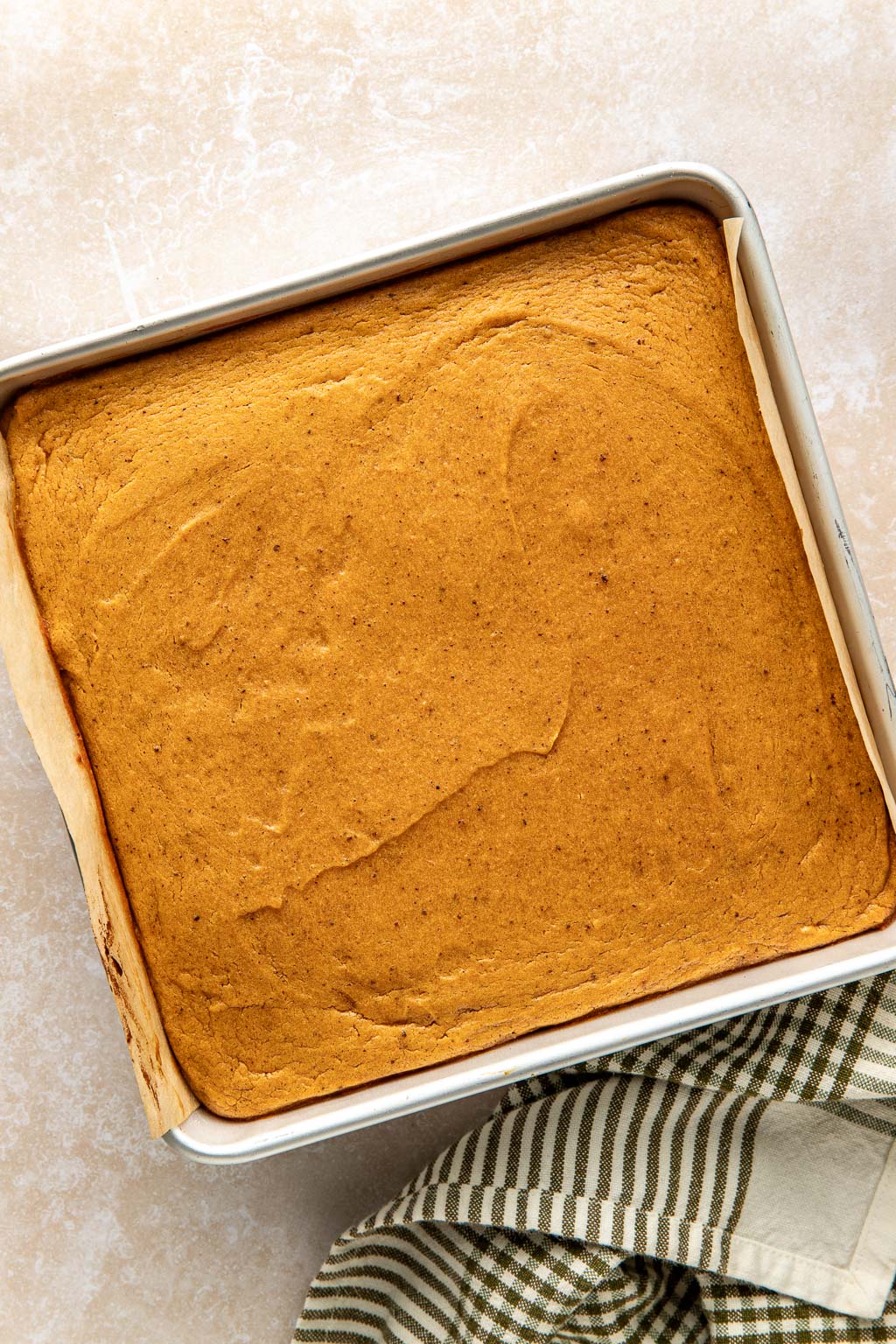 Unbaked sweet potato pie bars in a parchment lined baking dish. 