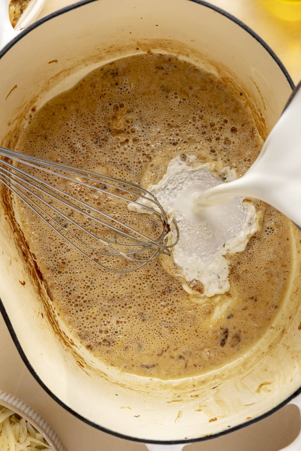Heavy cream being stirred into béchamel sauce. 