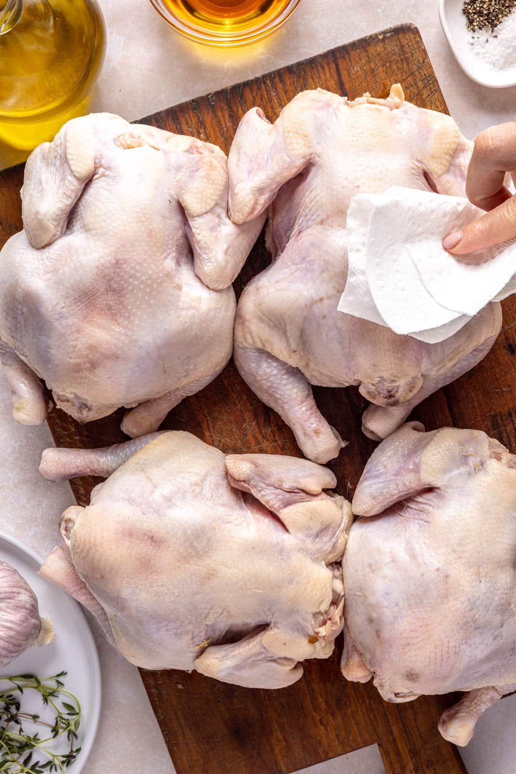 Cornish game hens being patted dry with a paper towel. 