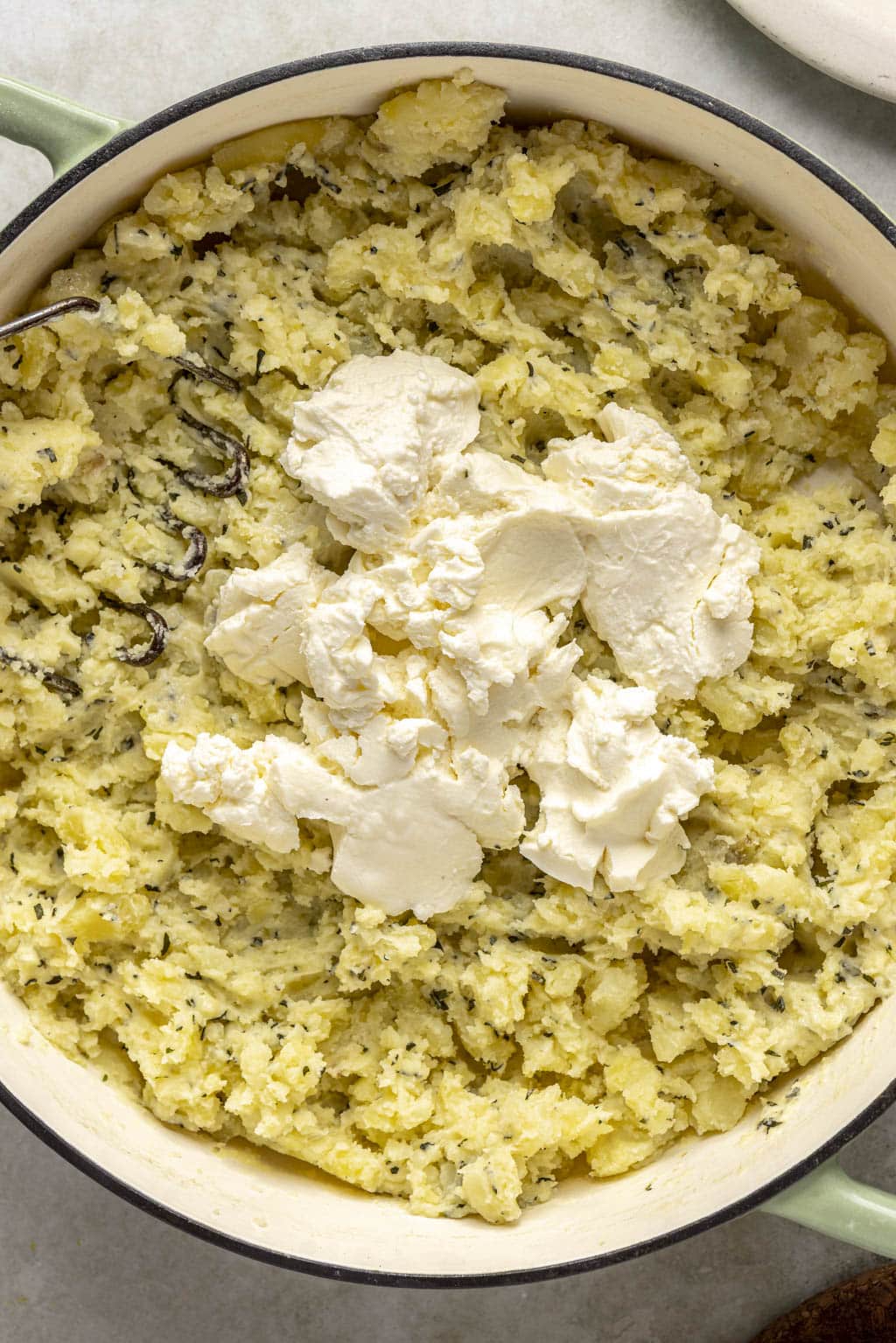 Mascarpone cheese added to mashed potatoes in Dutch oven. 