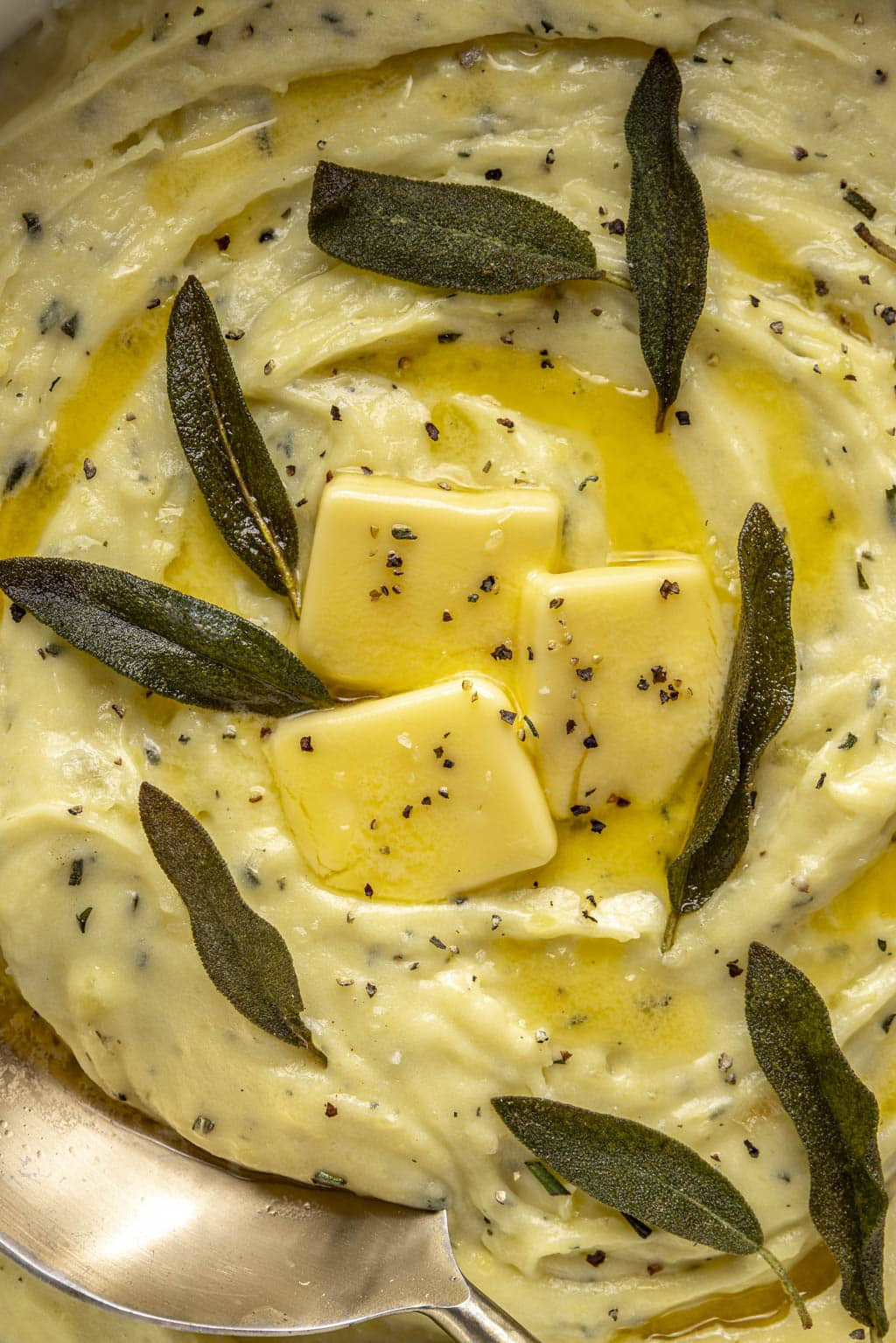 Close up overhead view of mascarpone mashed potatoes topped with sage leaves and butter. 