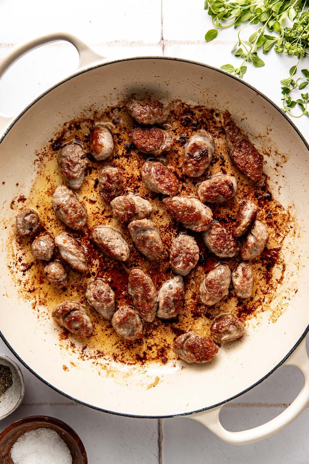 browned sausage in a white braiser skillet