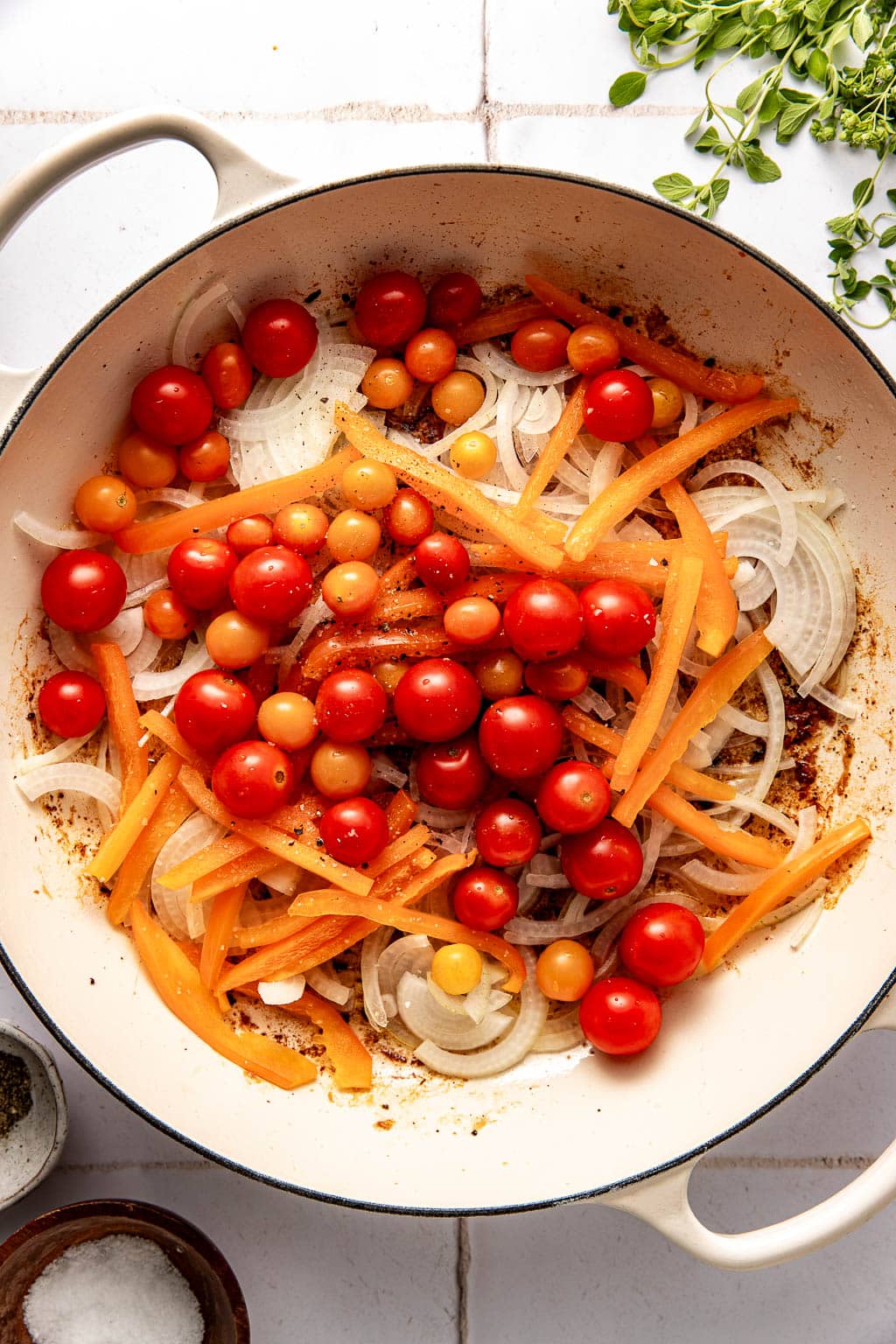 peppers, onions, and tomatoes in a skillet before cooking