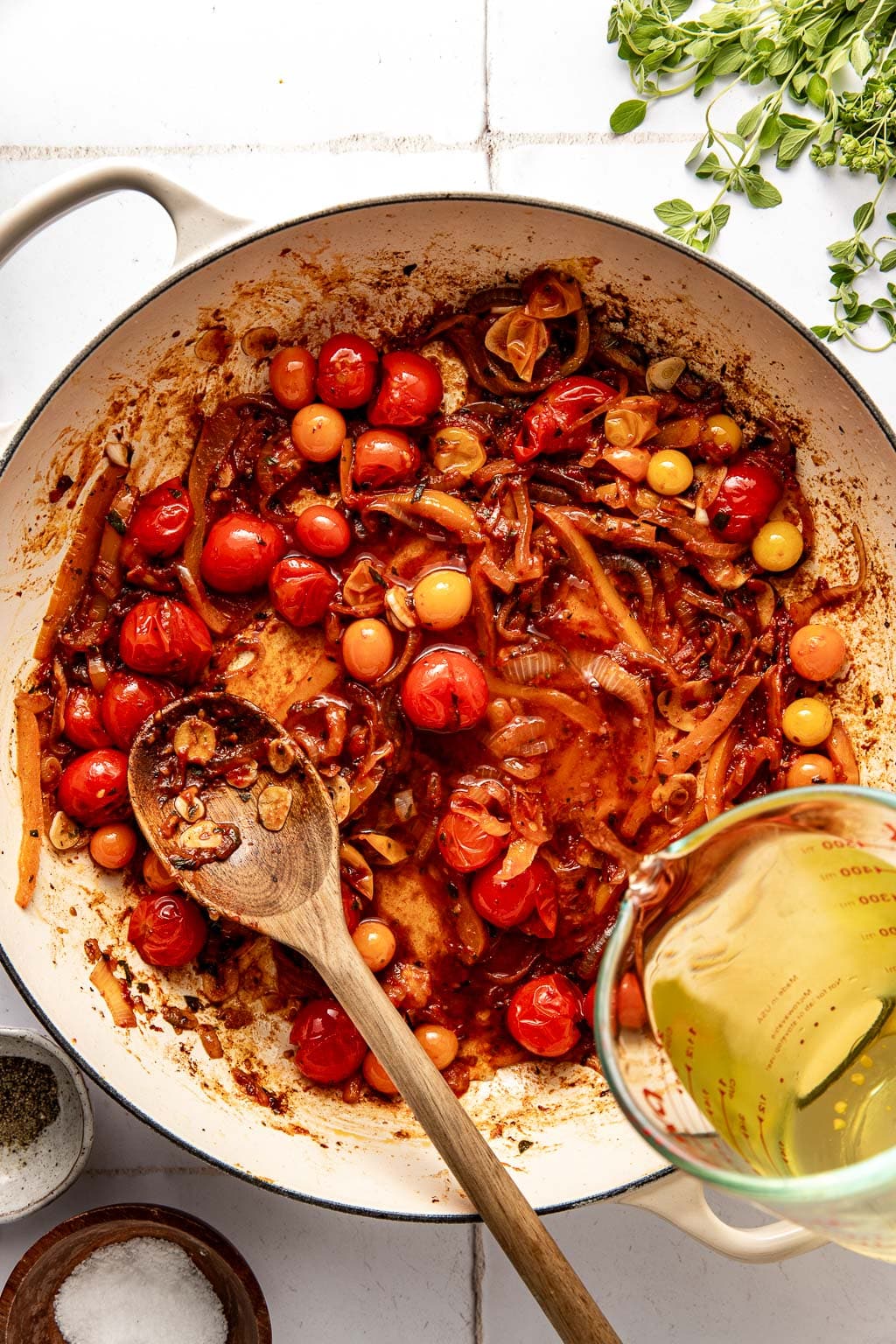 white wine being added to the skillet with the peppers, onions, and tomatoes