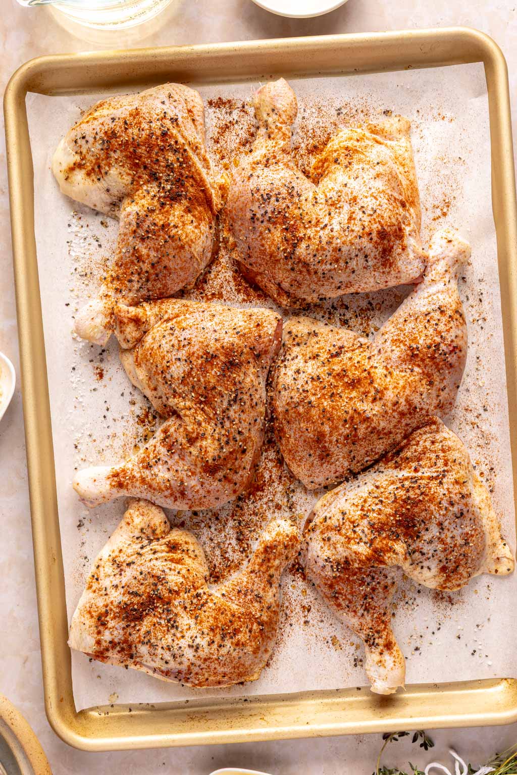 seasoned chicken leg quarters on a baking sheet