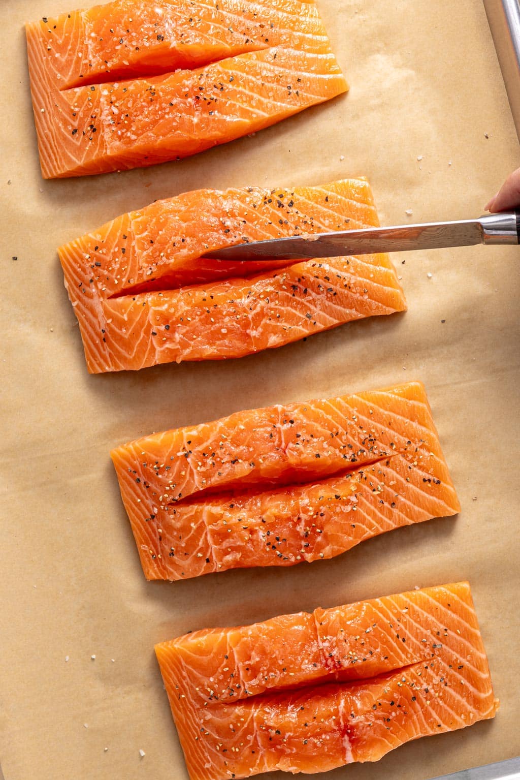 slicing the salmon filets on a baking sheet