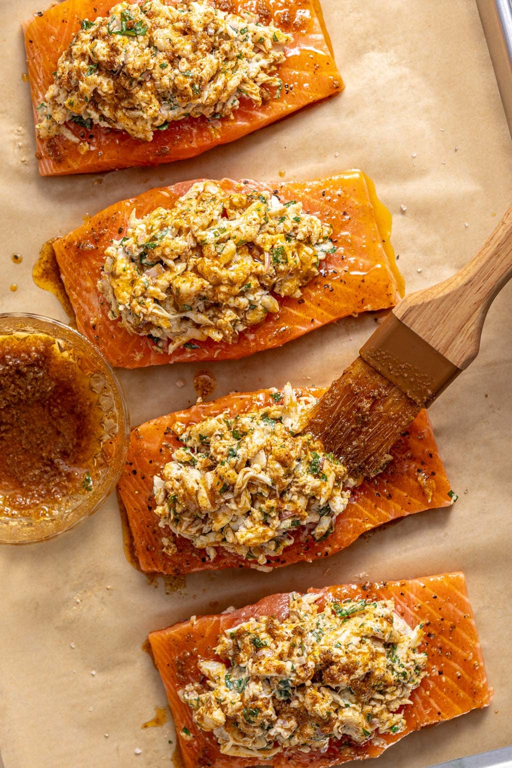 brushing salmon with old bay butter on a baking sheet