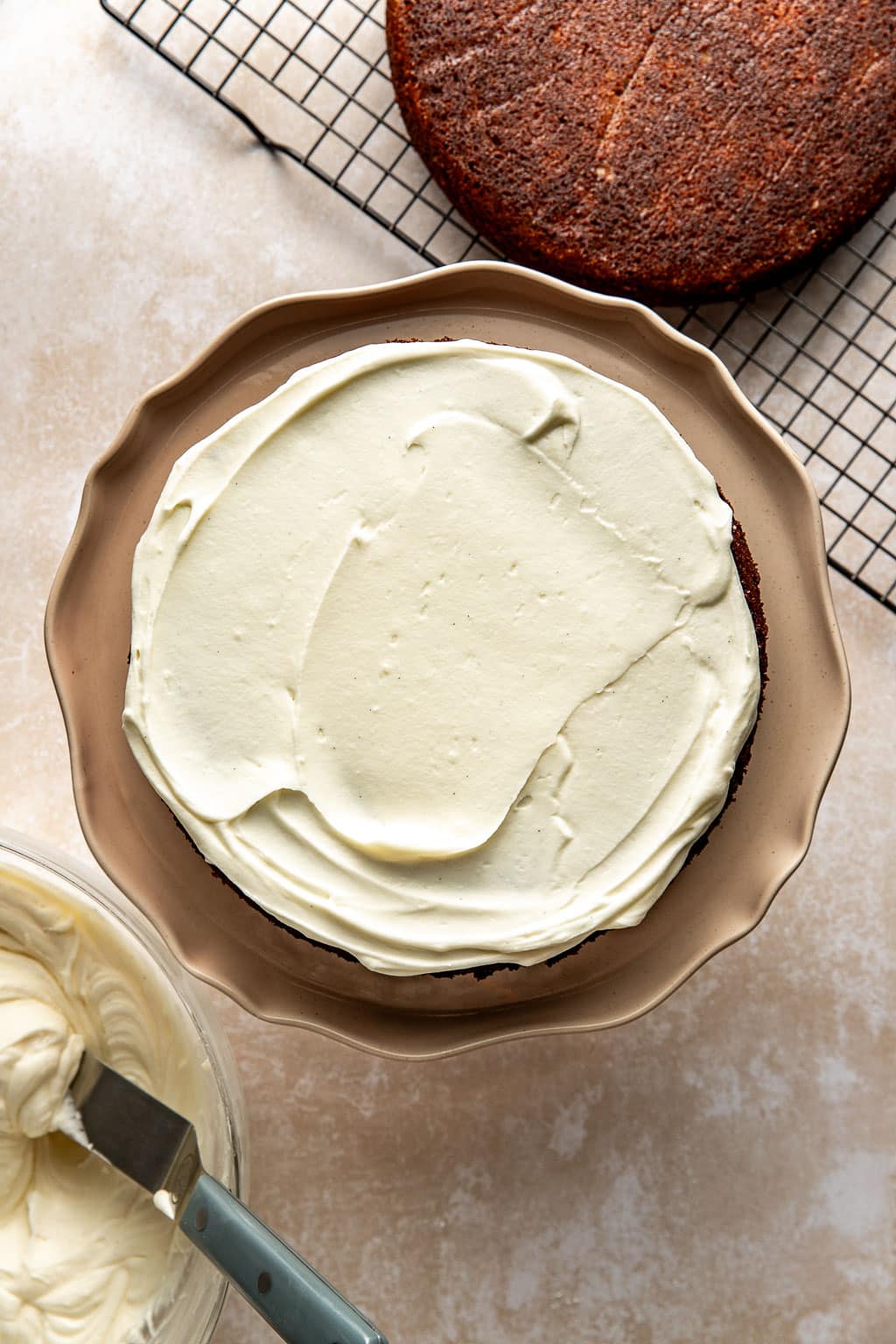 Cake being frosted with the cream cheese frosting. 