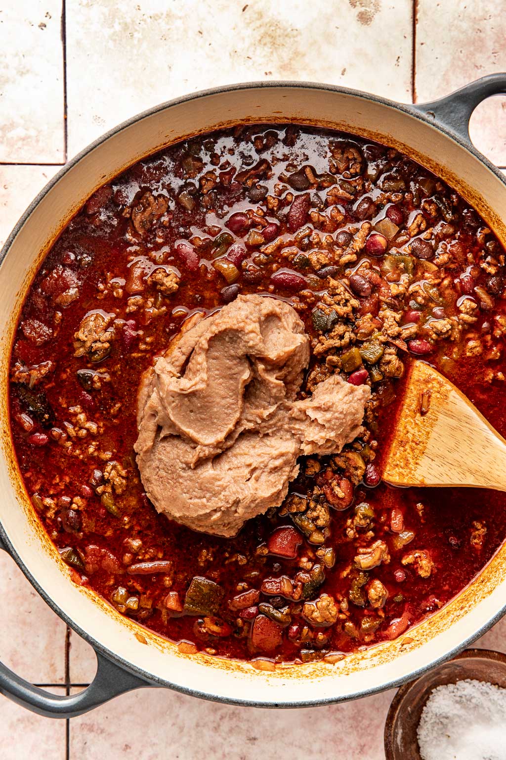 refried beans being added to the chili